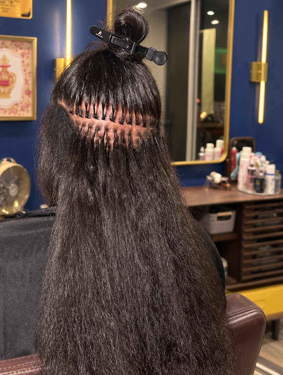 Close-up of individual K-tip extensions installed on textured dark hair inside Bodega Beauty NY