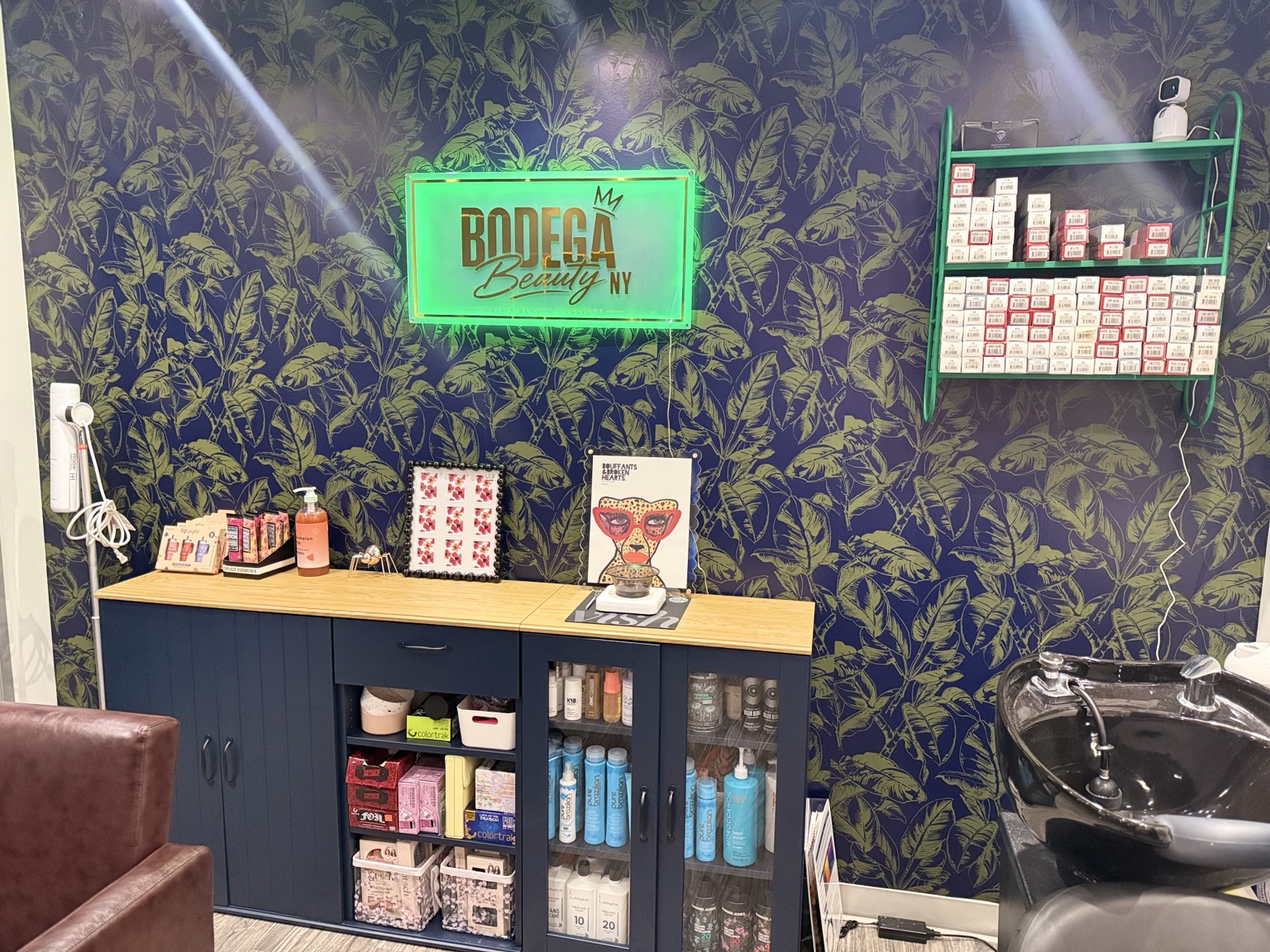 Interior of Bodega Beauty NY featuring the illuminated salon sign, botanical wall and color bar